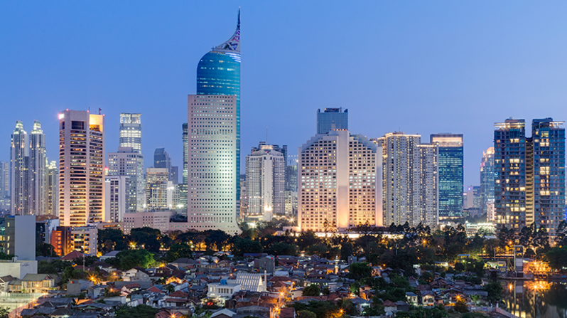 Indonesien: Aufnahme von Jakarta in der Abenddämmerung, kleine Häuser mit Bäumen vor der Skyline großer Hochhäuser Indonesien: Aufnahme von Jakarta in der Abenddämmerung, kleine Häuser mit Bäumen vor der Skyline großer Hochhäuser