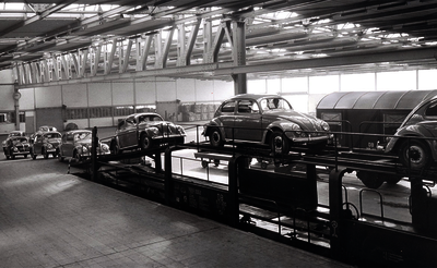 Historical picture VW transshipment in a warehouse: A large hall where Beetles are driven onto railway wagons.