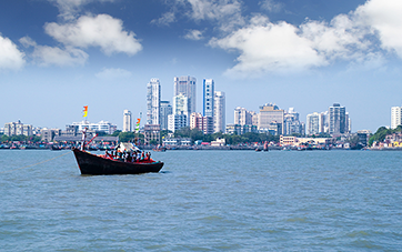 India: Skyline of Mumbai, in the foreground a moving colourful ship