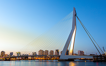  Niederlande: Skyline Rotterdam in Abenddämmerung, die Erasmus-Brücke ist im Vordergrund zu sehen 
