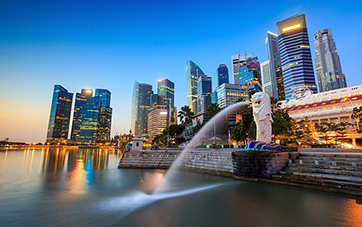 Singapur: Aufnahme von Singapurs Skyline mit erleuchteten Bürogebäuden, im Vordergrund der Merlion Park  